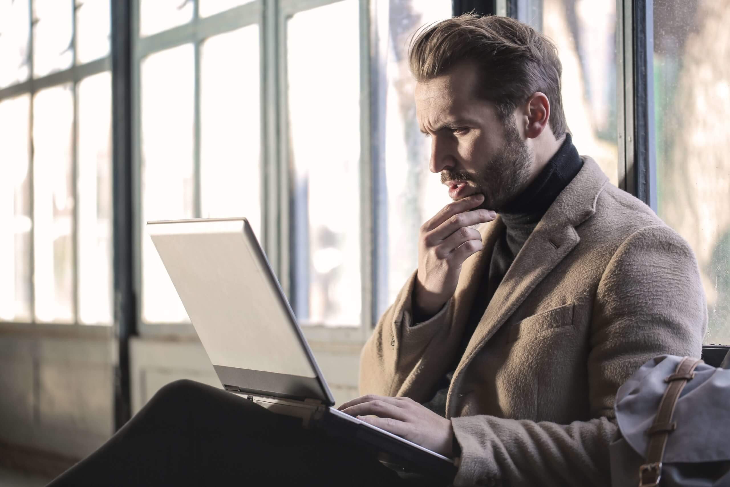 man-wearing-brown-jacket-and-using-grey-laptop-874242-scaled