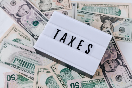 Sign reading "taxes" laying on a pile of paper money