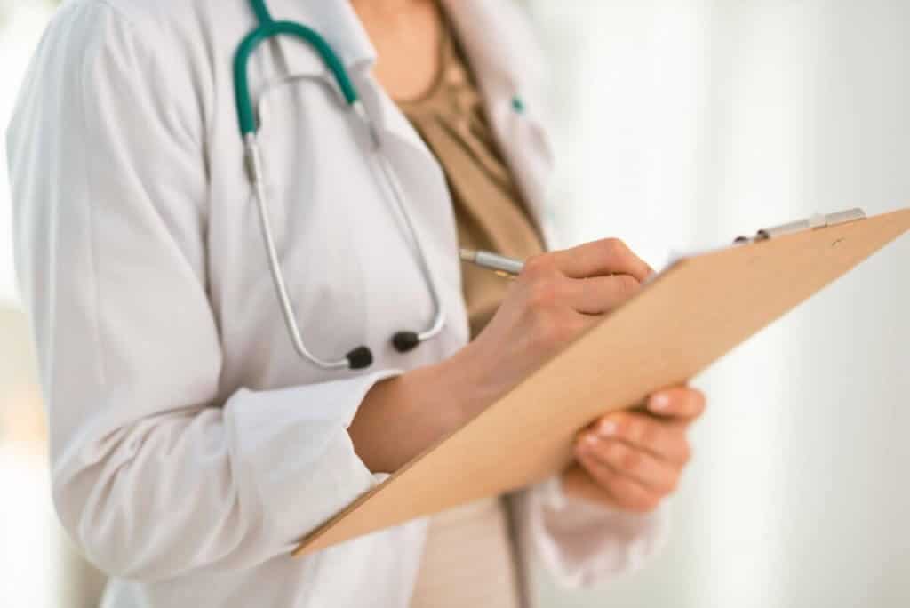 Doctor filling out paper on clipboard