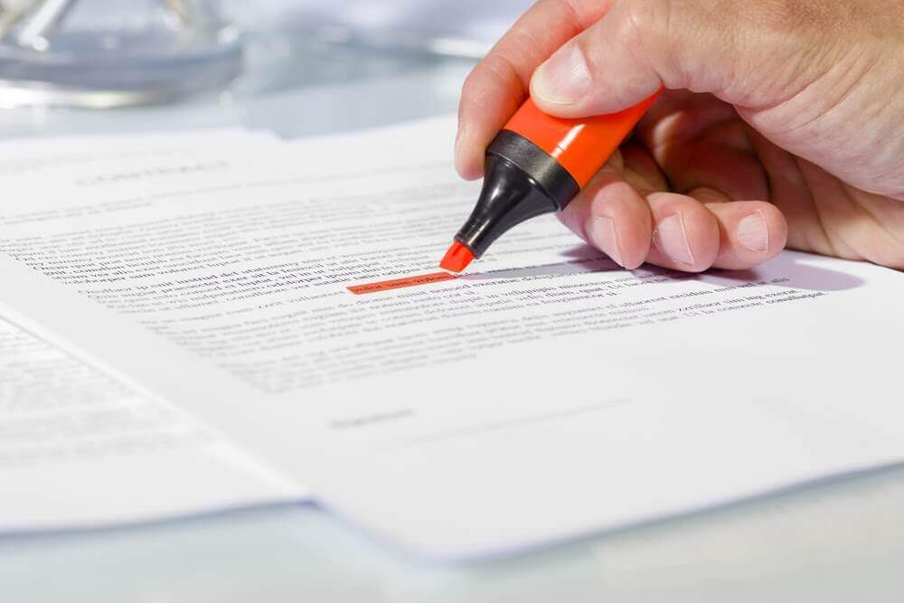 Person highlighting text on paper contract