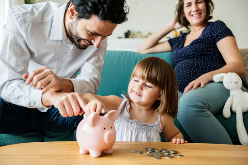 Father and and daughter placing coins in piggy bank