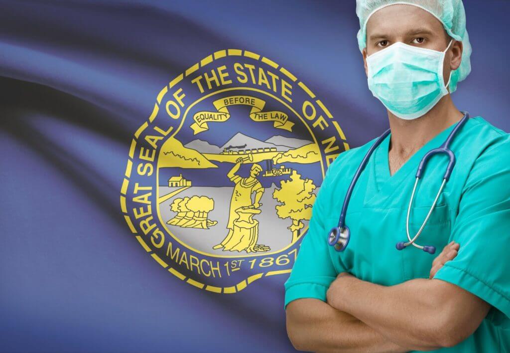 How to Get a Medical License in Nebraska Physician standing in front of Nebraska state flag