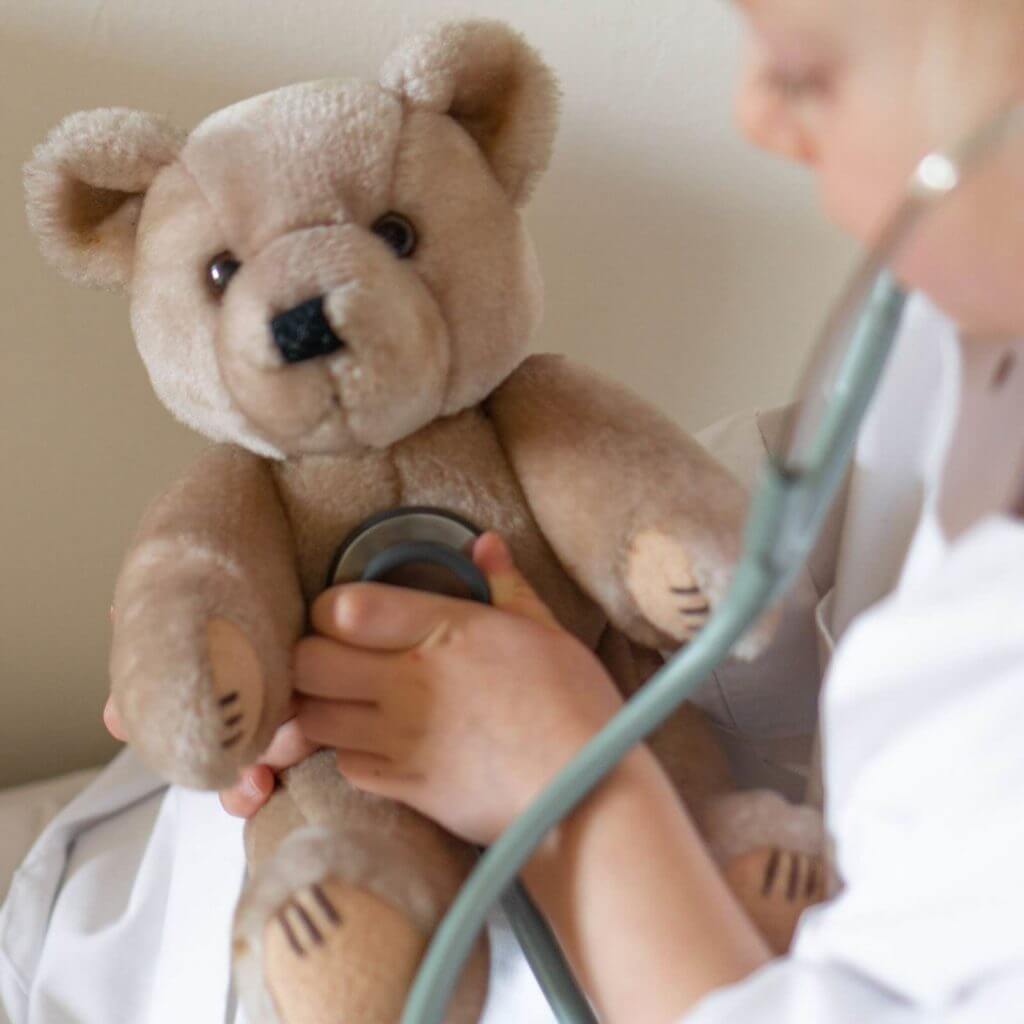 Physician using stethoscope on teddy bear