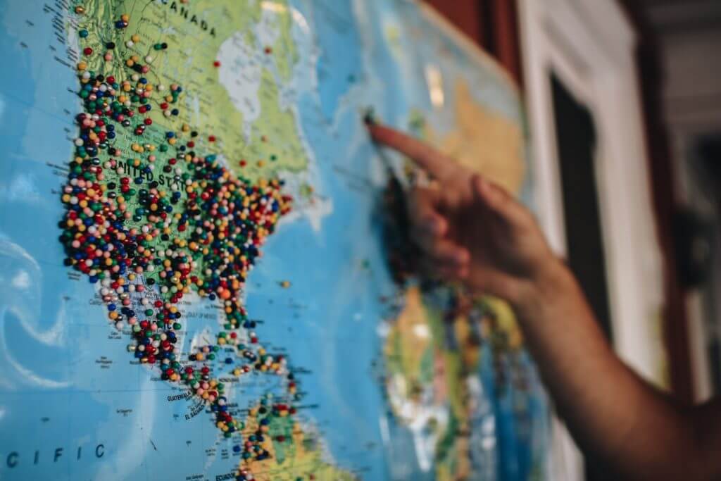 Person pointing at map with pins in it