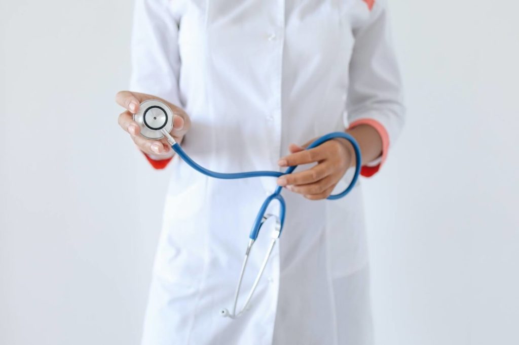 Physician in lab coat holding stethoscope