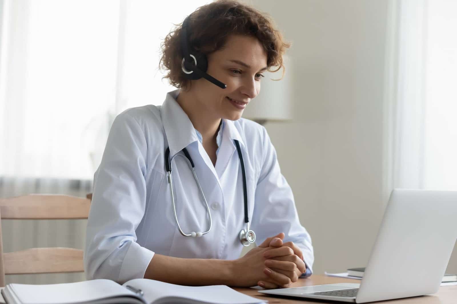 Physician wearing headset sitting at desk with laptop