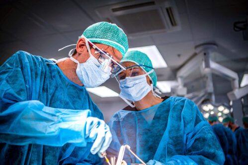 two surgical residents holding retractors and scalpels during a surgical simulation lab