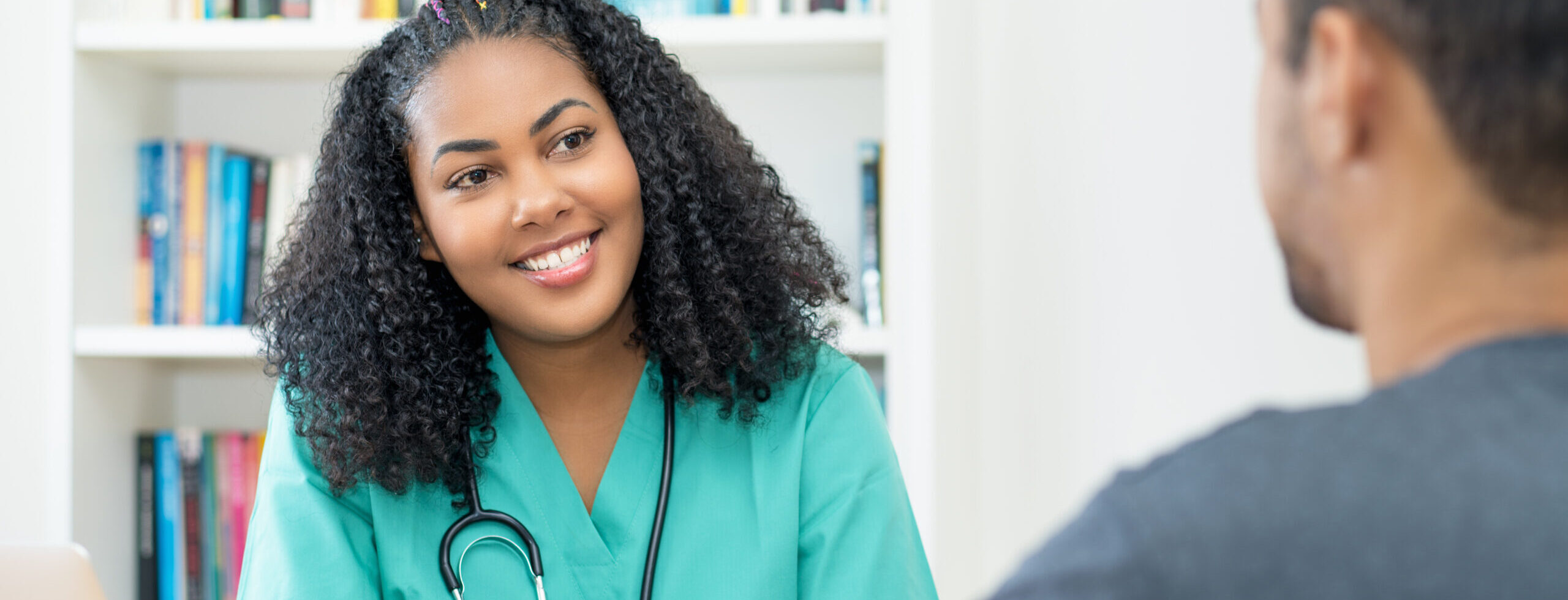 laughing latin american female nurse or young doctor listening to patient